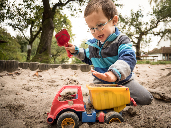 Kind beladet SpielzeugLKW mit Sand